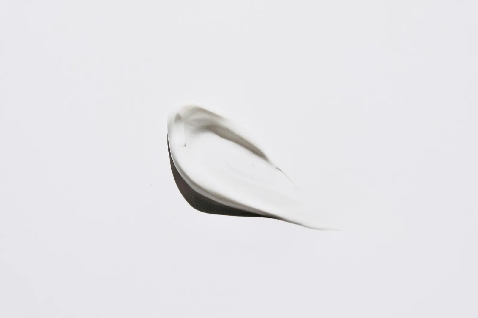A single swipe of white cream on a pale surface, its ridge casting a soft shadow