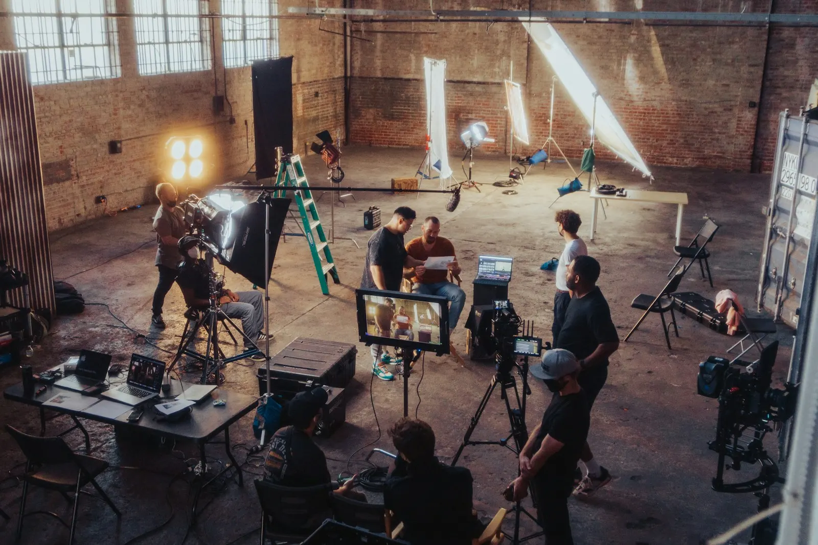 Crew, lights and a monitor set up inside a brick warehouse location