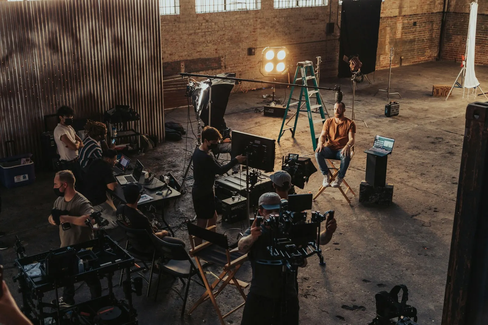 Crew filming a seated actor inside a brick warehouse location