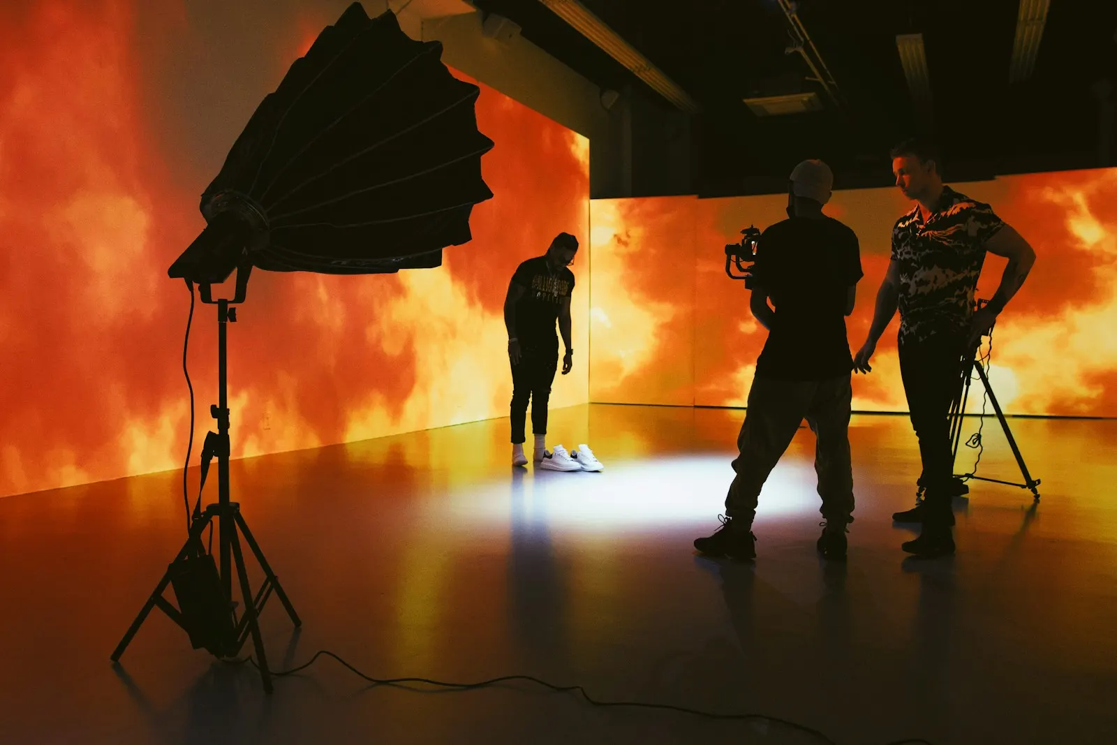 Crew filming on a set lit by a glowing orange LED wall and a soft box