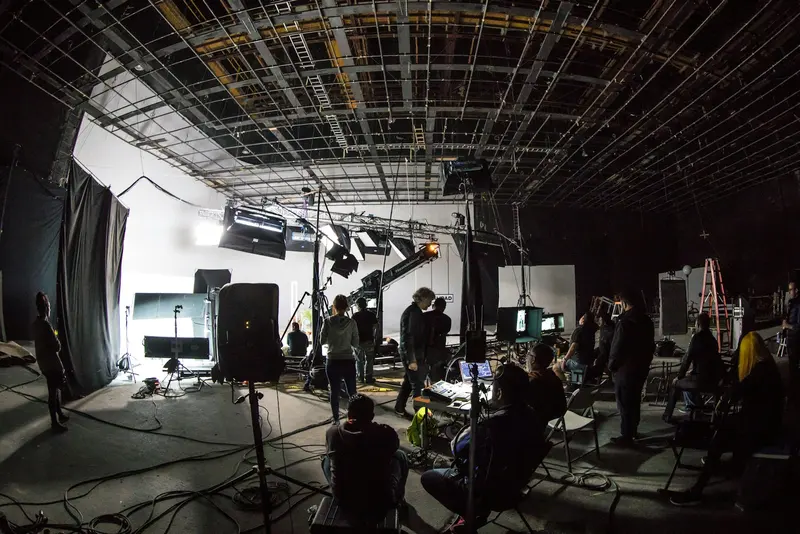 Film studio floor with lighting rigs and crew at work