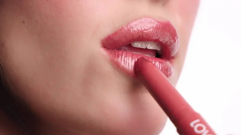 Macro film frame of a glossy lip conditioner being applied to a lower lip