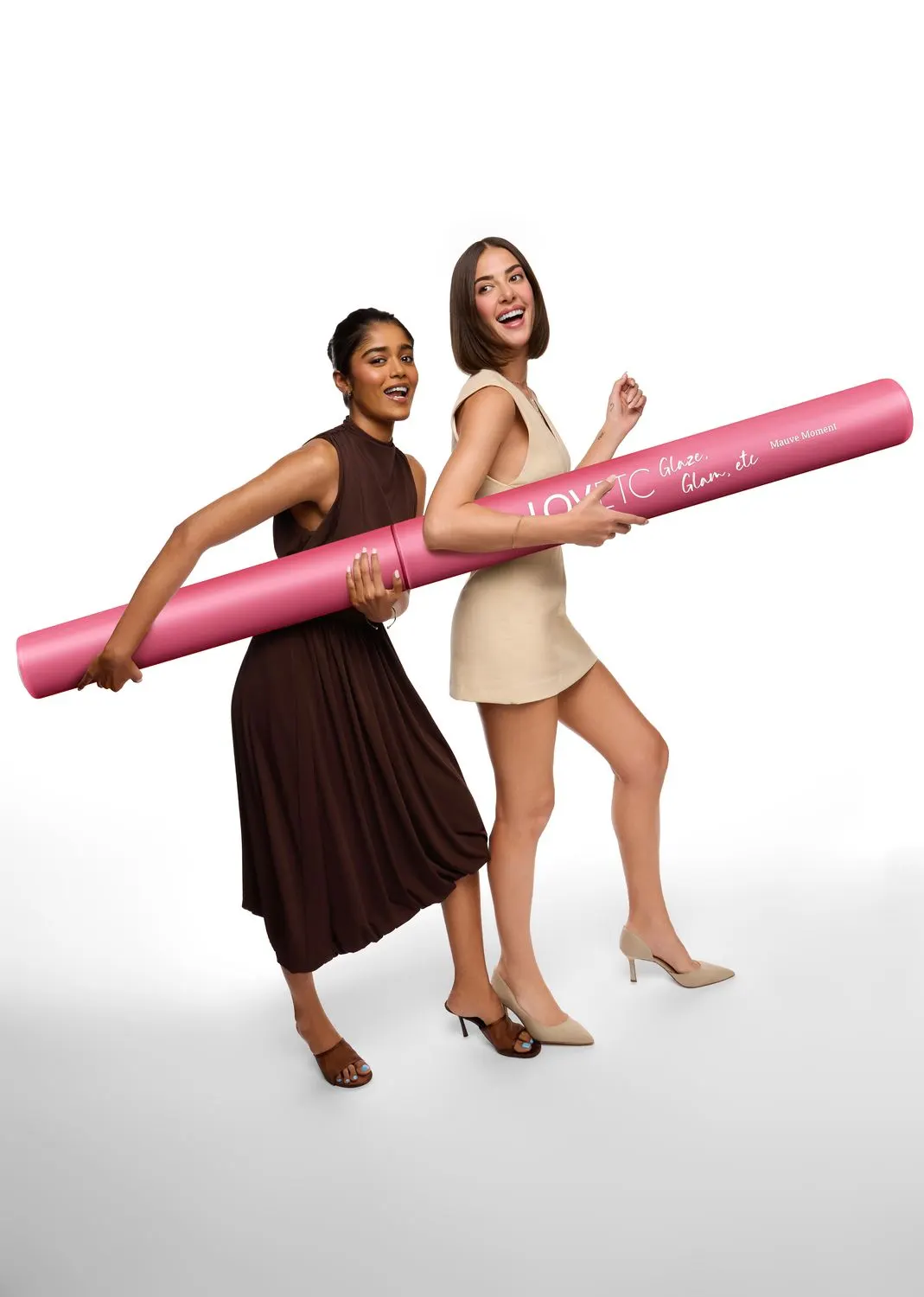 Two models laughing as they carry an oversized pink lip conditioner prop