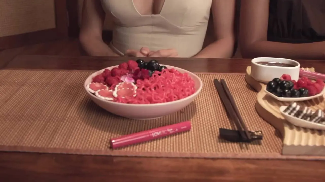 Lip conditioner plated beside a bowl of pink noodles on a restaurant table set