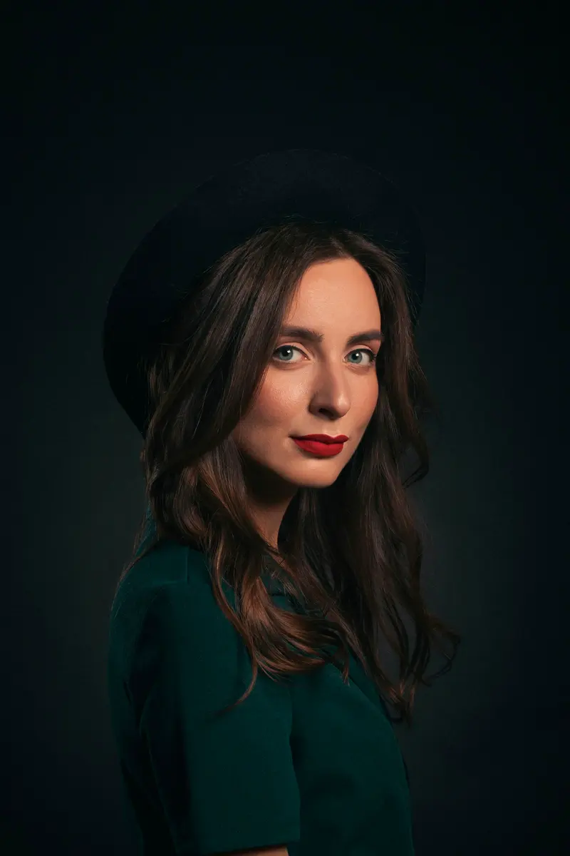 Portrait of a woman in a dark hat against a dark background