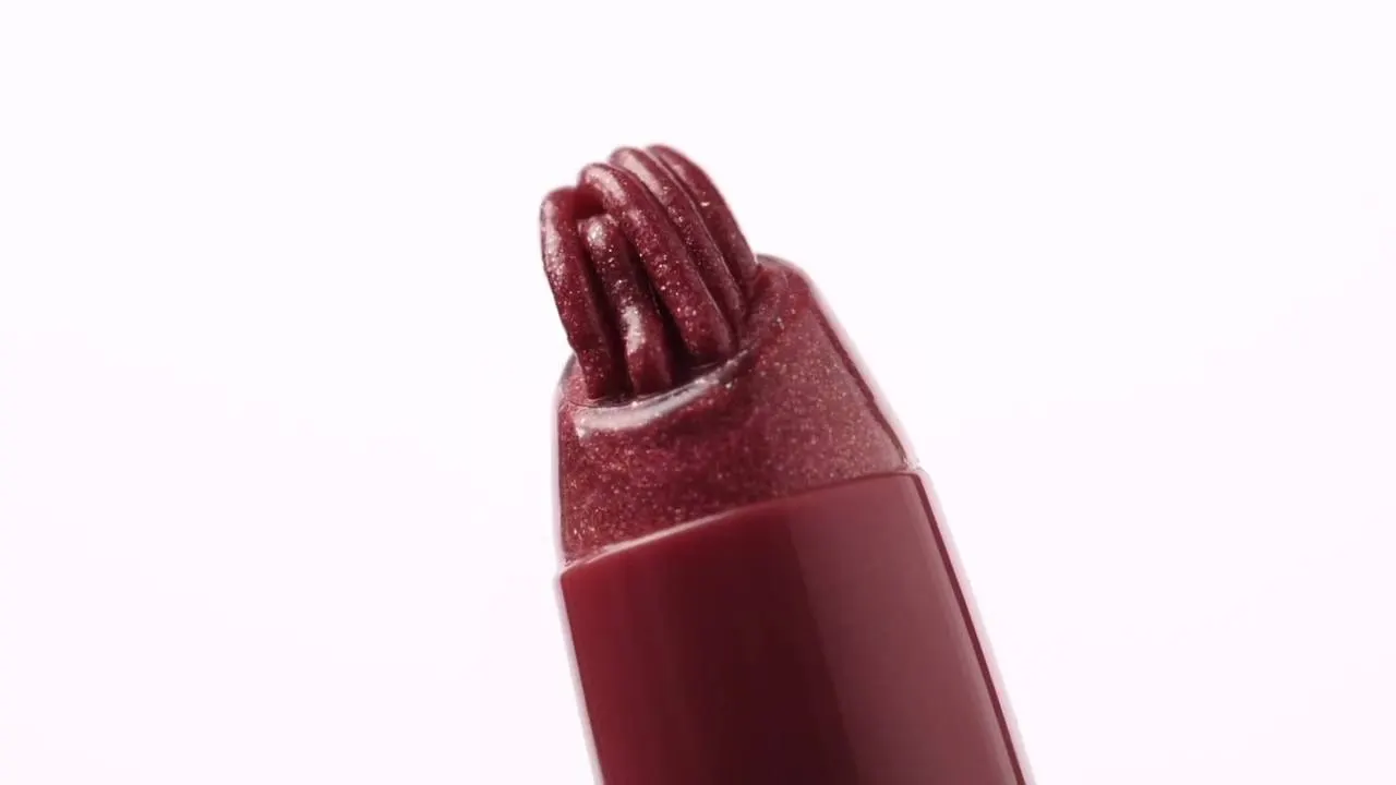 Macro close up of a shimmering berry lip conditioner bullet on white
